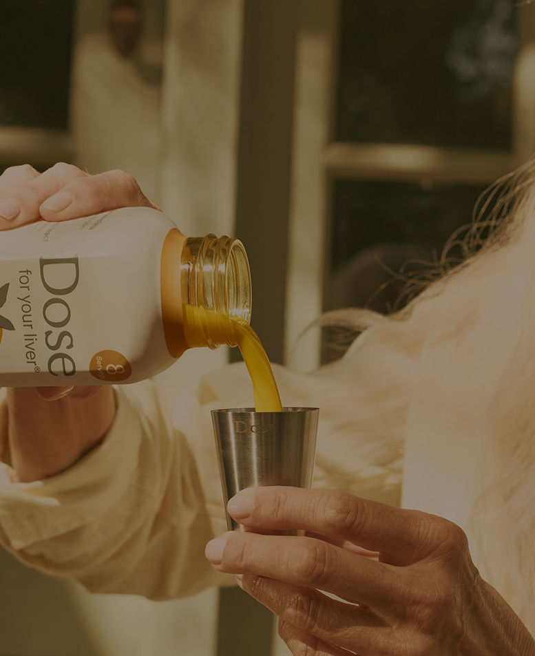 Hand pouring Dose liquid supplement into a steel measuring cup
